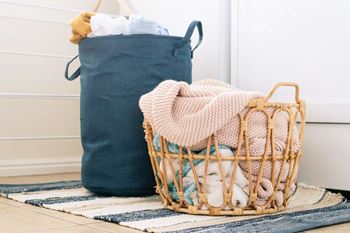 A basket of clothes next to a blue laundry bag